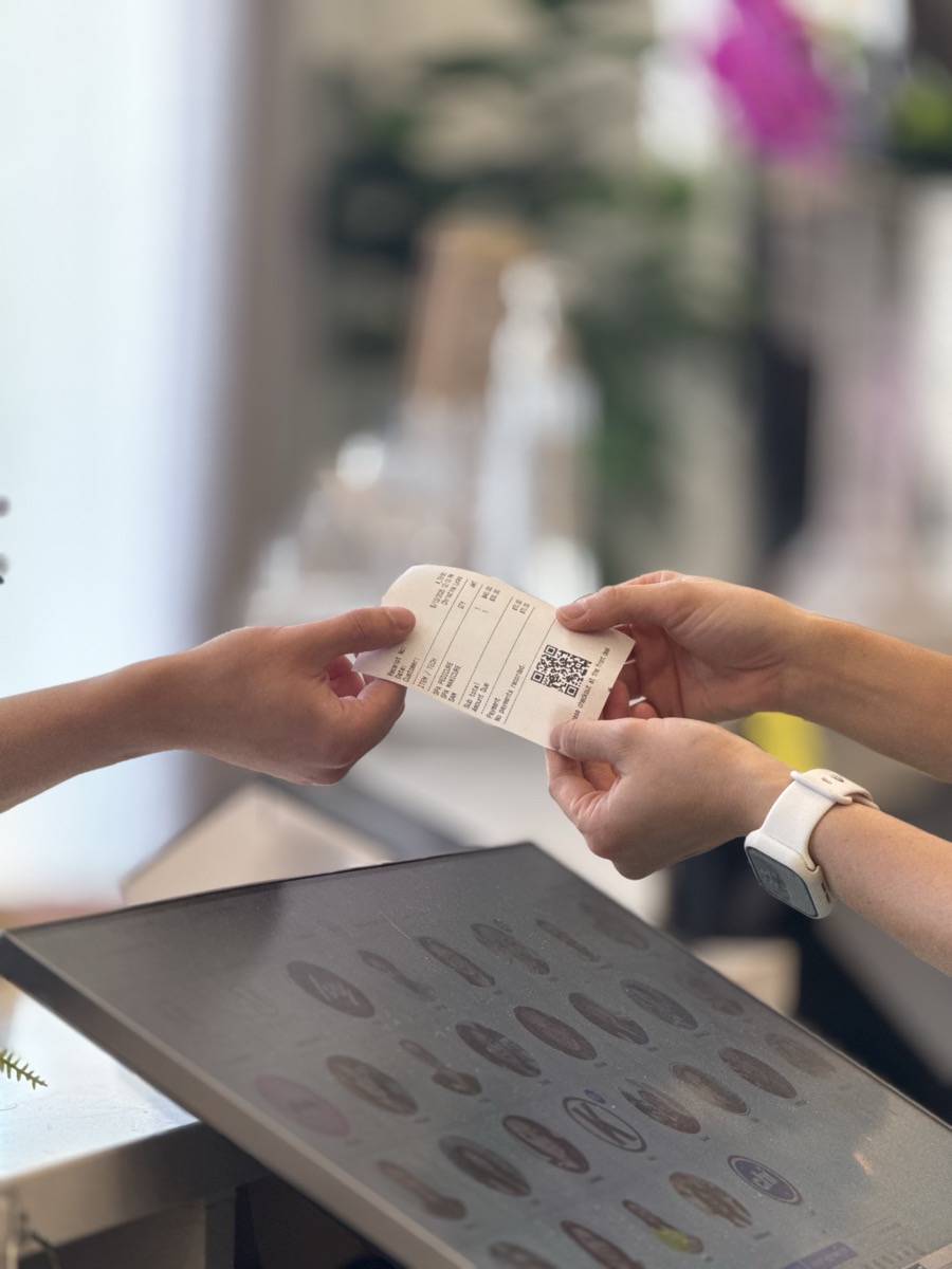 Salon team member handing a printed checkout ticket to a customer